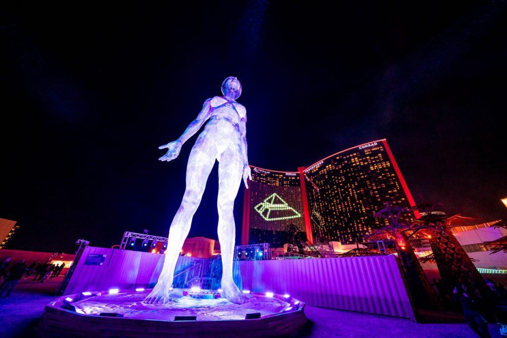 large metal women's shape illuminated in front of a modernist building in las vegas at night