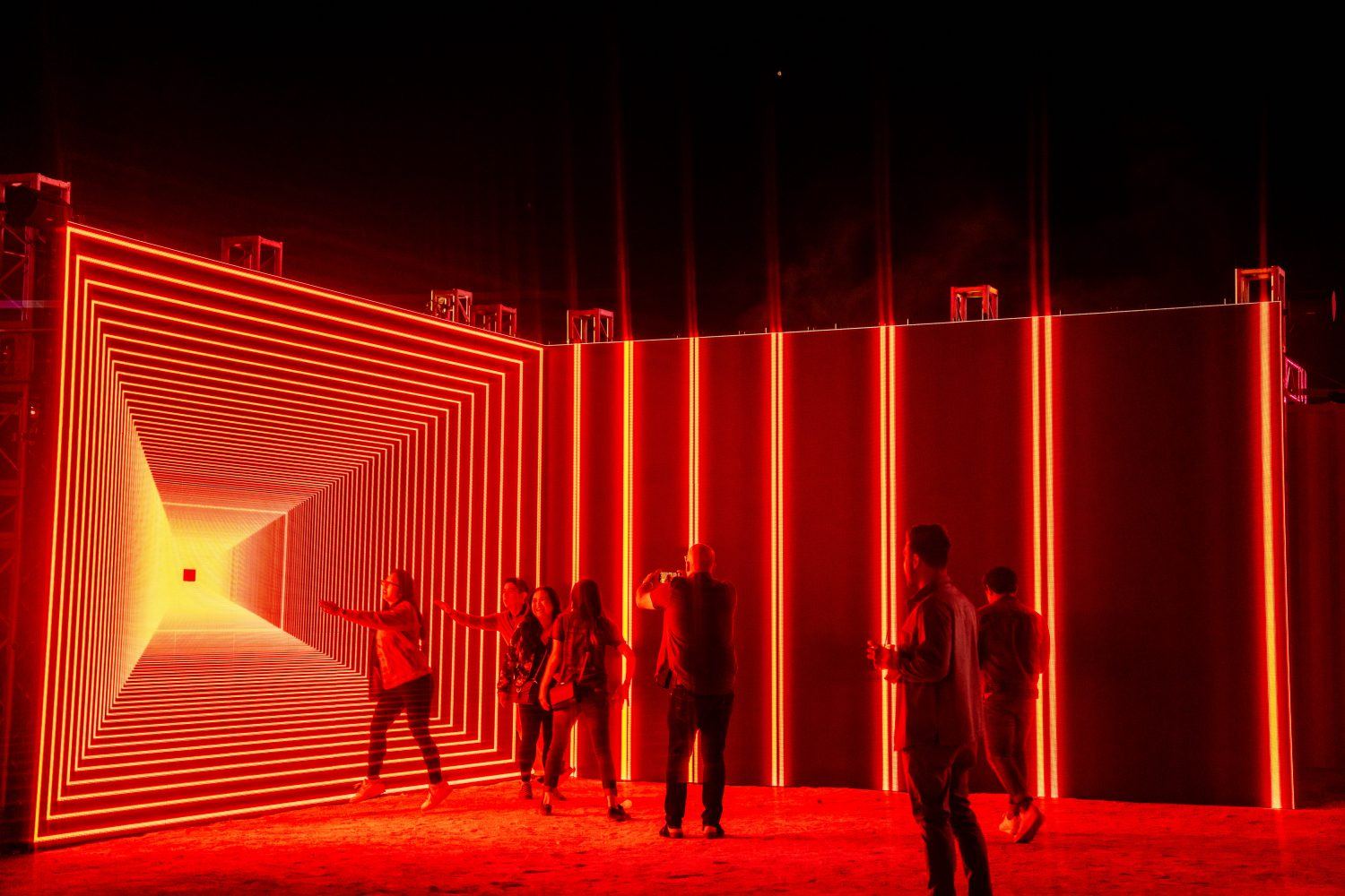 a group of people interacting with a red light art installation