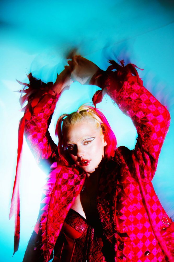 close up of woman in pink suit standing against a blue background