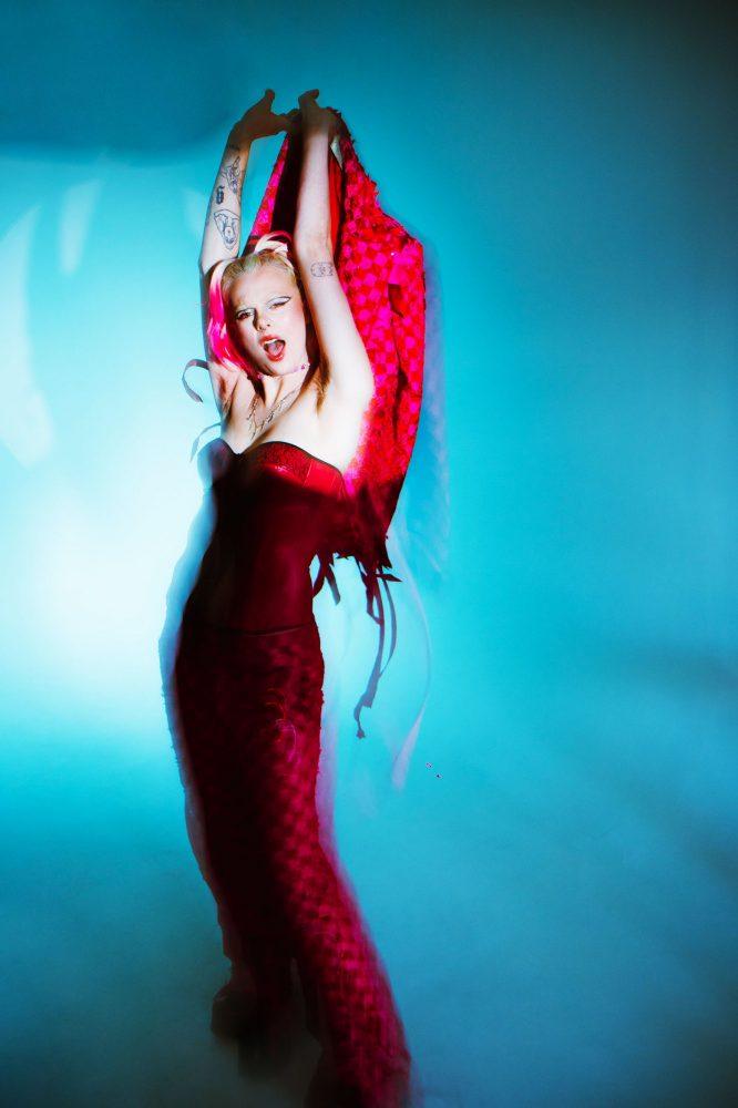 woman in pink stands against a blue background