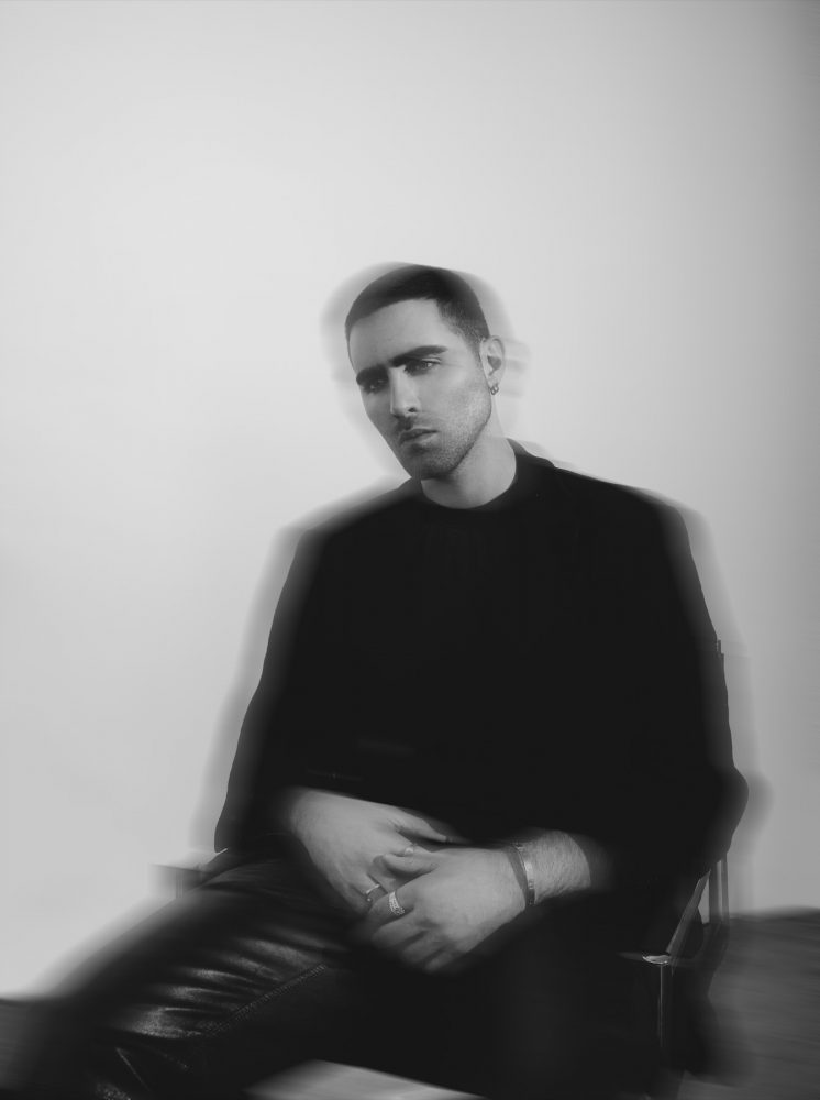 black and white image of a man sitting wearing black blury
