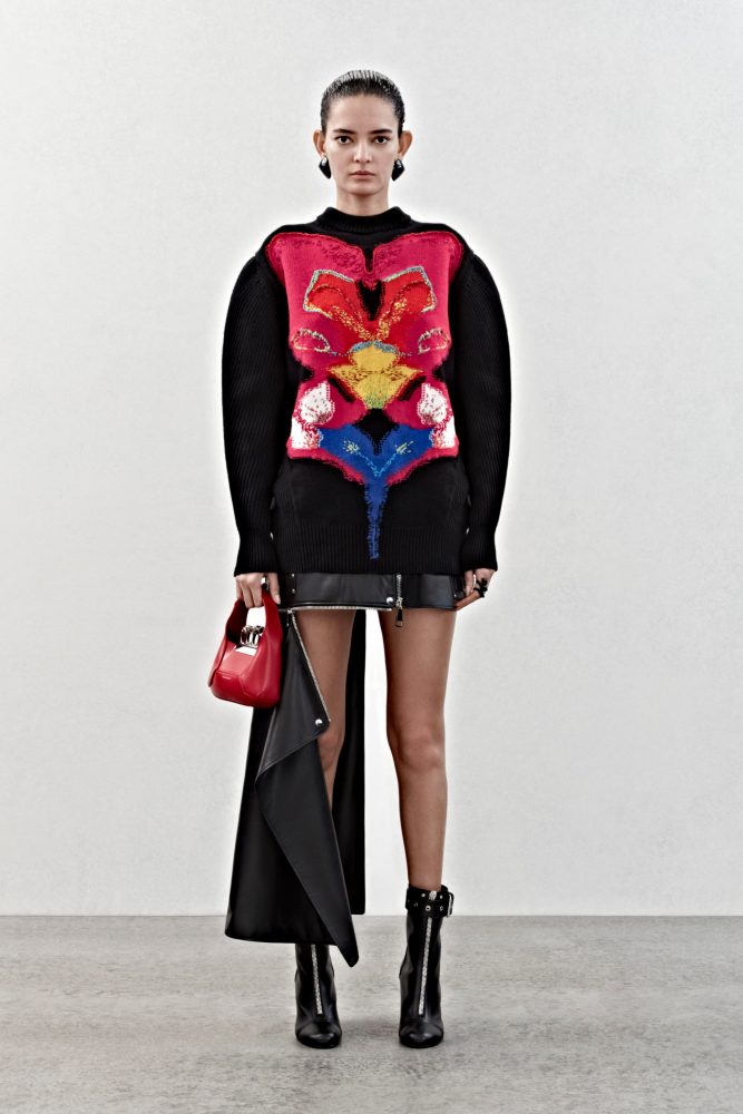 An oversized jumper in black wool with a solarized mirrored orchid intarsia and a slashed biker skirt in black leather.