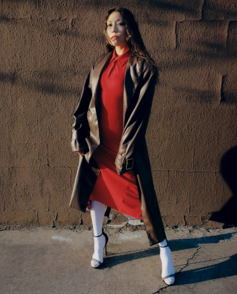 Sasami wears ROWEN ROSE coat and dress available at FWRD, CASADEI shoes, and FALKE tights. Written and Produced by BJ Panda Bear. Photographed by Andrew Friendly. Styled by Britton Litow. Hair: Paul Rizzo using Bumble and Bumble. Makeup: Nichole Servin using Westman Atelier and Rare Beauty. Stylist Assistant: Maddie Collins.